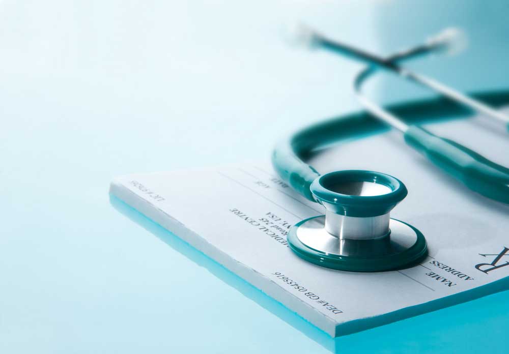 A stethoscope lying on top of a medical subscription pad